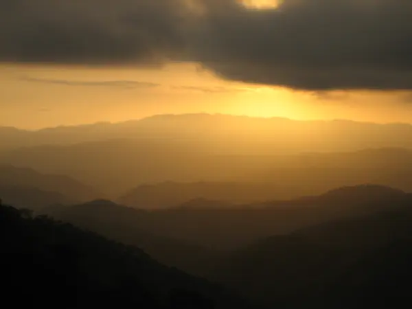 A colorful photograph of a sunset on top of a mountain in Latin America