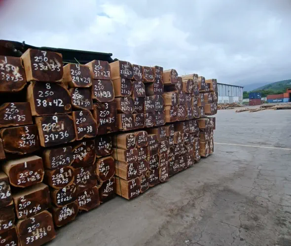 A photograph of stacks of rough sawn squares laying outside